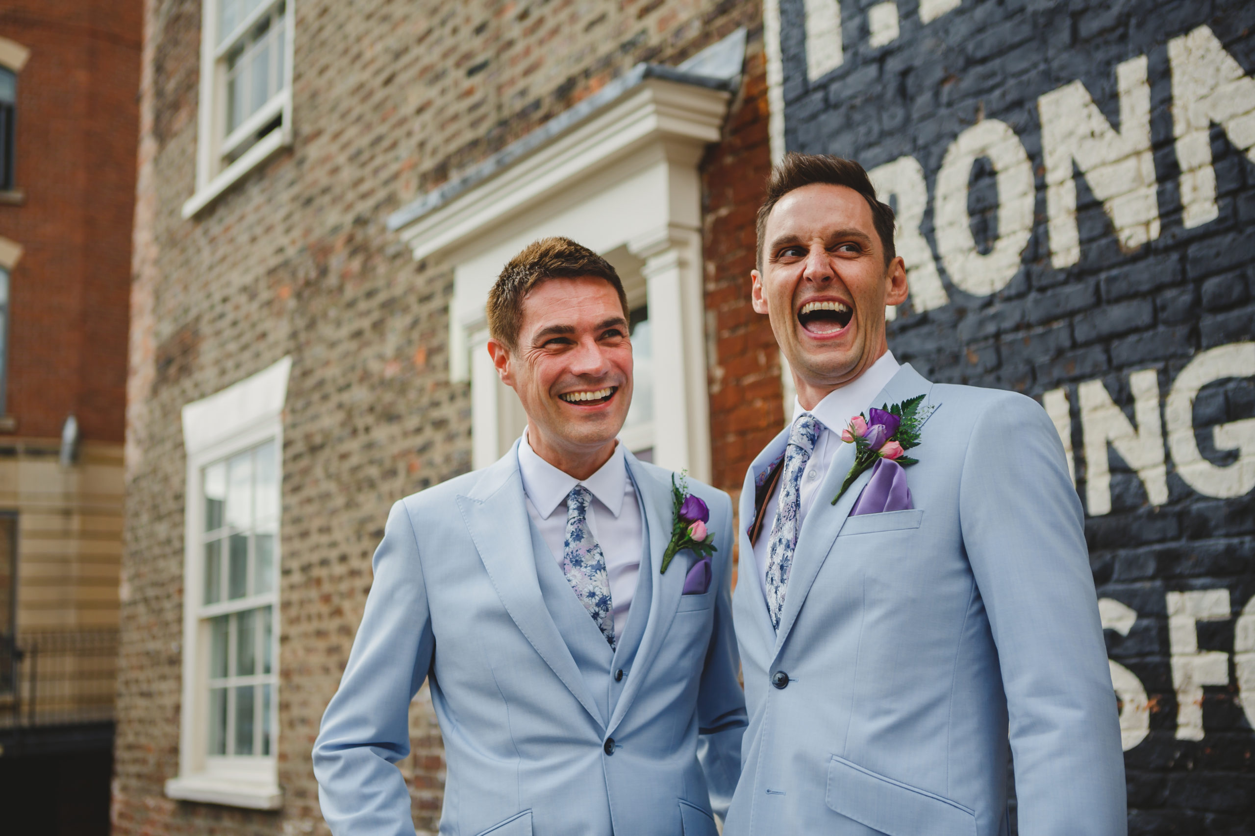 a gay couple in matching blue suits laughing in York