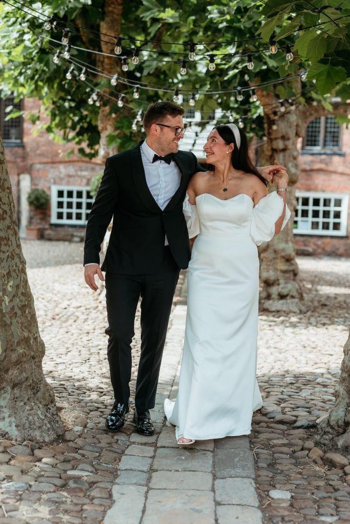 Bride and groom walking outdoors under string lights at York Register Office.