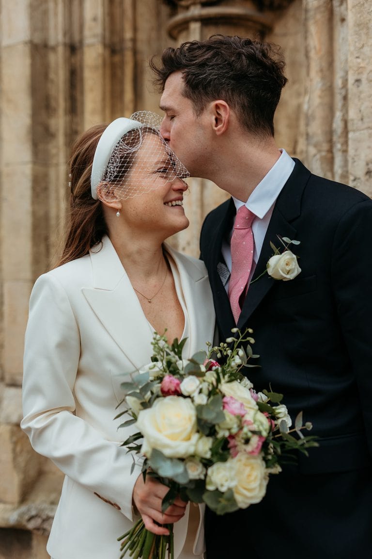 Bride and groom sharing a kiss at a historic wedding venue.