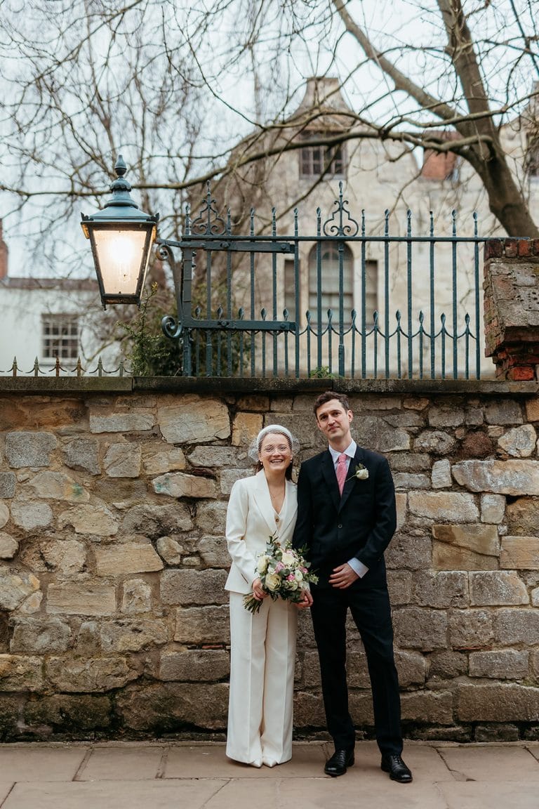 Wedding couple standing outdoors near stone wall at Mine & Thine Staging.