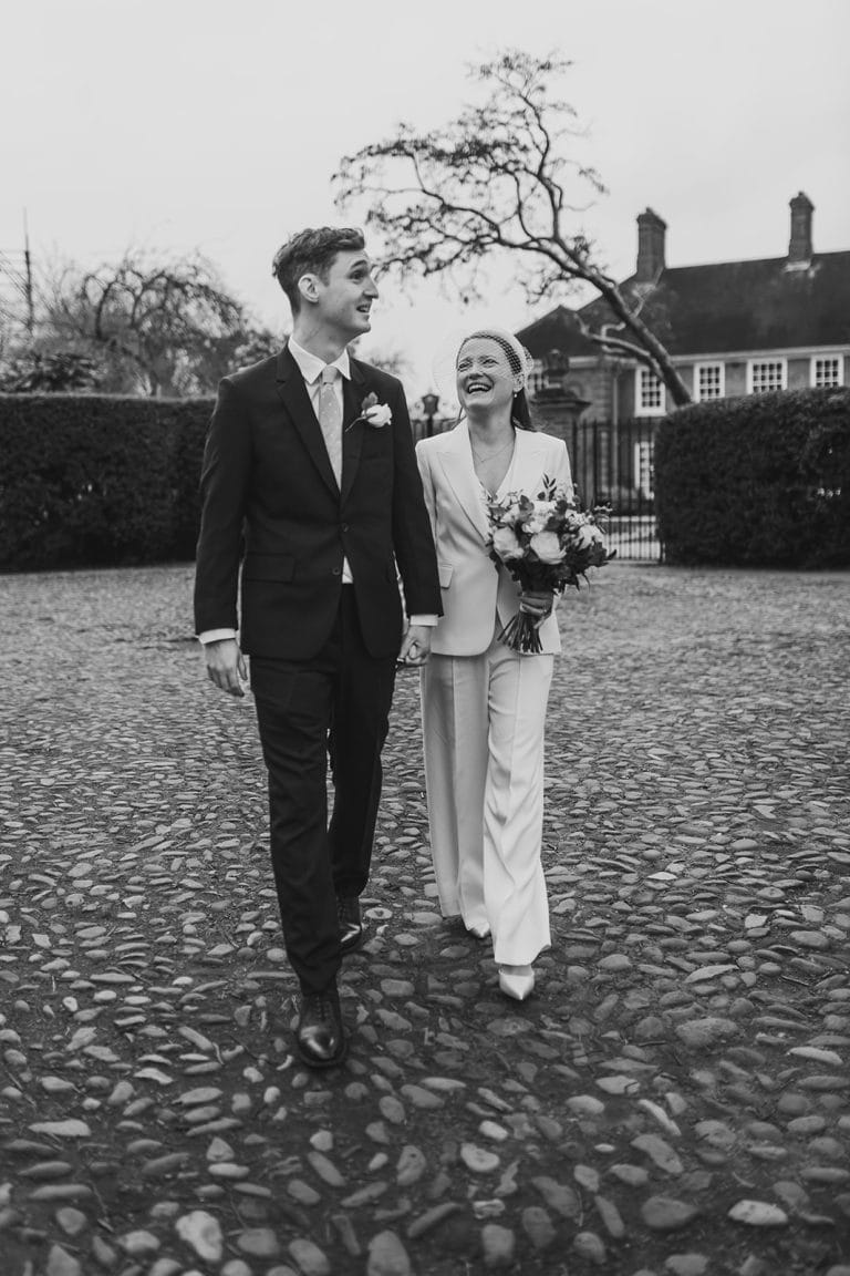 Happy wedding couple walking outdoors with bouquet in hand.